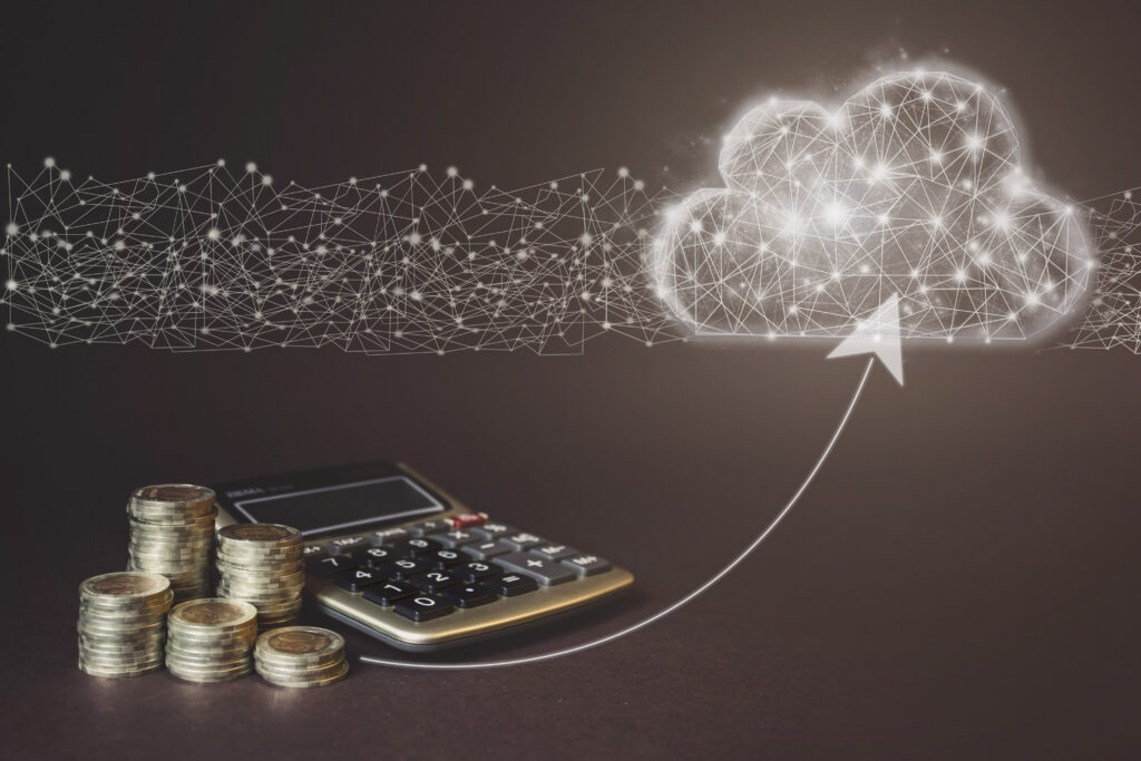 Stacks of coins and a calculator sit on a table. An arrow points to a digital cloud above, symbolizing cloud computing and financial growth.