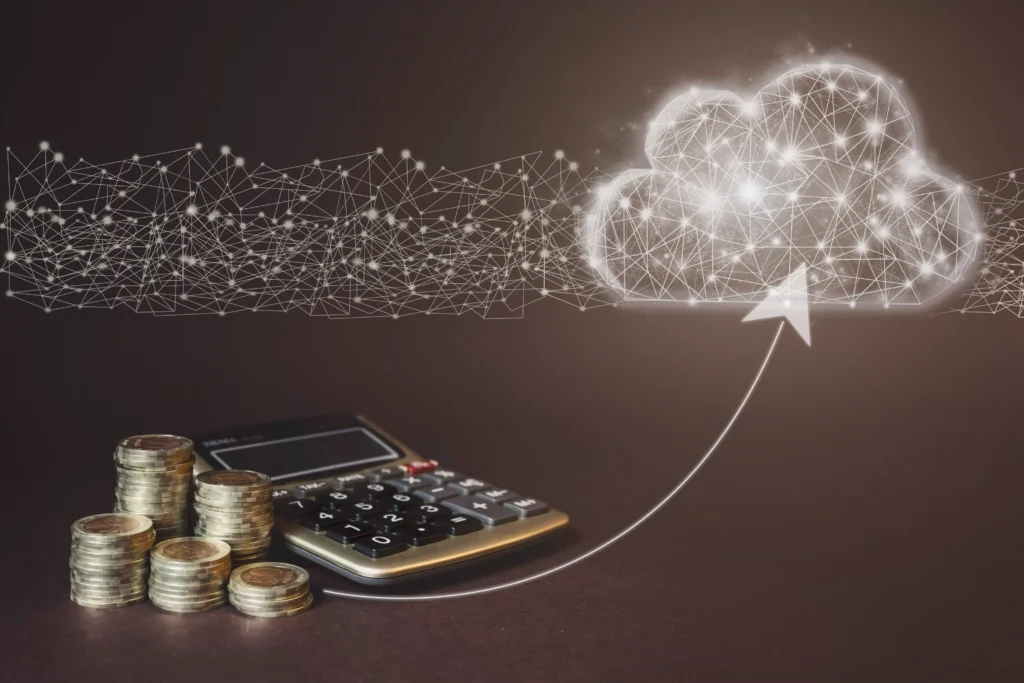Coins stacked beside a calculator with a digital arrow pointing to a glowing cloud, suggesting financial data moving to cloud storage.-NetsecTechnologies, Cloud Cost Optimization